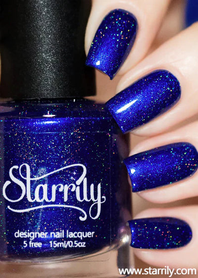 Heart of the Ocean by Starrily, sapphire blue holographic with pink-rainbow micro-fleck scatter, bottle held in a light skin tone hand