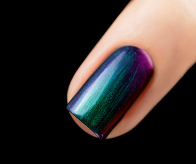 Death Wish by Starrily, multichrome metallic showing vivid violet-purple to teal-green to blue-indigo shift with linear shimmer, on a light skin tone hand