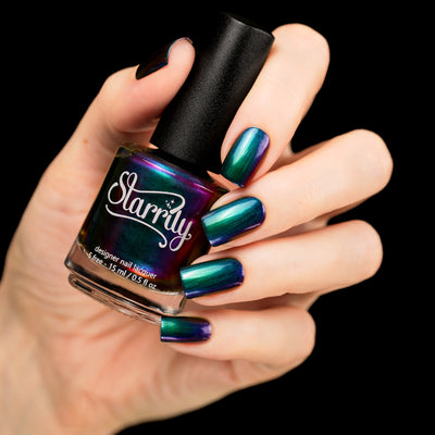 Death Wish by Starrily, multichrome chrome-like finish mid-shift from teal green through dark purple to electric blue, bottle held in a light skin tone hand