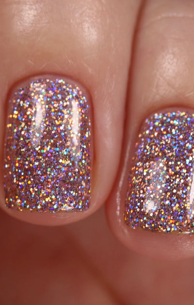 Dollhouse by Starrily, rose-pink holographic micro-glitter with silver prismatic reflections in bright daylight, on a light-medium skin tone hand