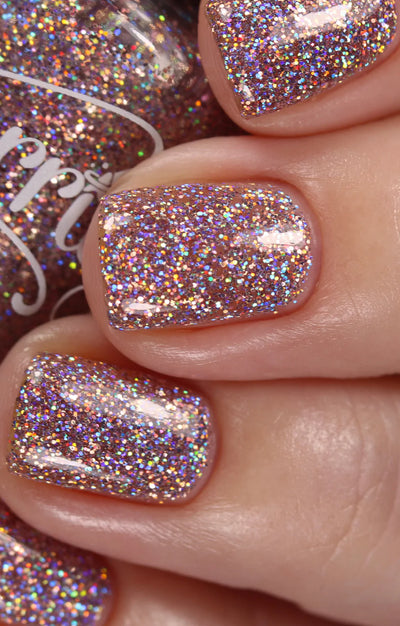 Dollhouse by Starrily, dusty rose pink holographic glitter in clear base with violet-toned rainbow scatter, on a light skin tone hand