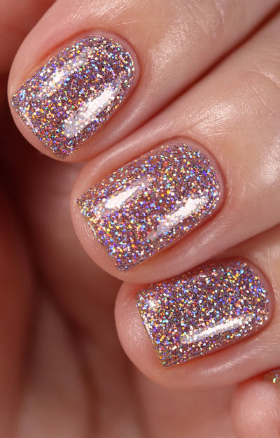 Dollhouse by Starrily, dense light pink holographic micro-glitter in clear base with prismatic rainbow scatter under studio lighting, on a light-medium skin tone hand