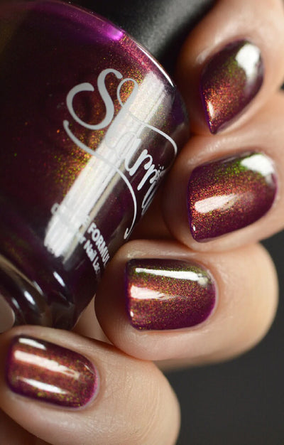 Dragon by Starrily, deep purple base with copper-to-green color-shifting shimmer, bottle held in a light-medium hand