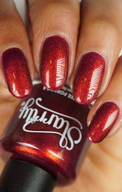 Dragon by Starrily, purple base reading deep crimson-red with vivid copper-orange shimmer in bright daylight, on a light-medium skin tone hand