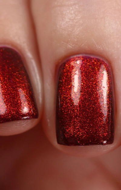 Dragon by Starrily, intense copper-red to orange shift over deep burgundy base under direct flash, on a light-medium skin tone hand