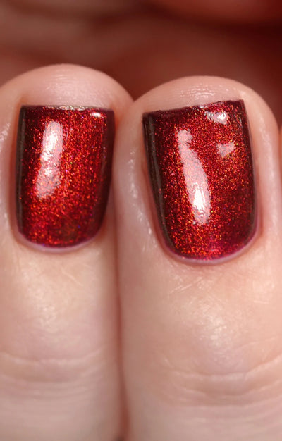 Dragon by Starrily, purple base blazing with copper-red metallic shimmer under direct flash, deep burgundy-purple in shadow, on a light skin tone hand
