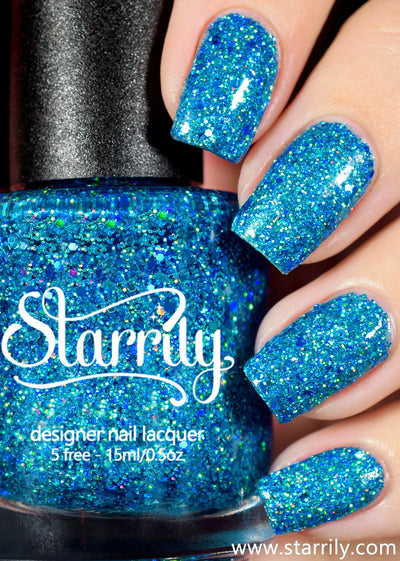 Blitzen by Starrily, cerulean blue jelly with mixed-size teal and holographic hex glitter, bottle held in a light skin tone hand