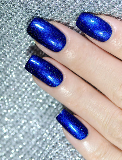 Heart of the Ocean by Starrily, royal sapphire blue holographic with gold, green, and rainbow spectral micro-flakes across eight nails, on a light skin tone hand