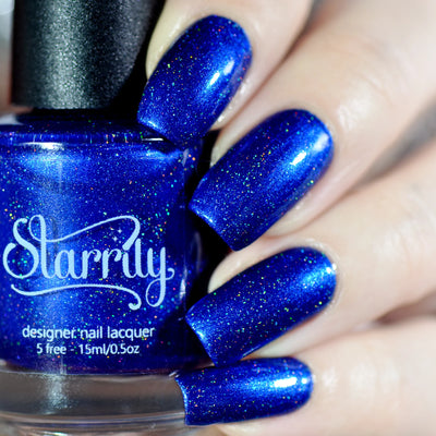 Heart of the Ocean by Starrily, sapphire blue holographic with multicolored micro-flake shimmer, bottle held in a light skin tone hand