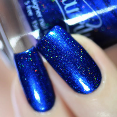Heart of the Ocean by Starrily, sapphire blue holographic with vivid red-green-gold micro-flake scatter, on a light skin tone hand
