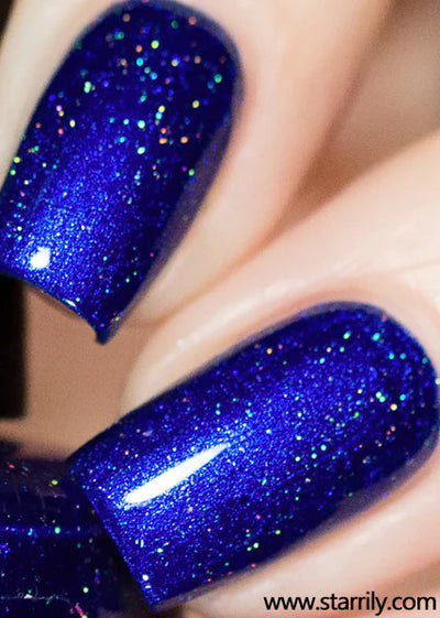 Heart of the Ocean by Starrily, deep sapphire blue holographic showing dense scattered holo sparkle under direct flash, on a light skin tone hand
