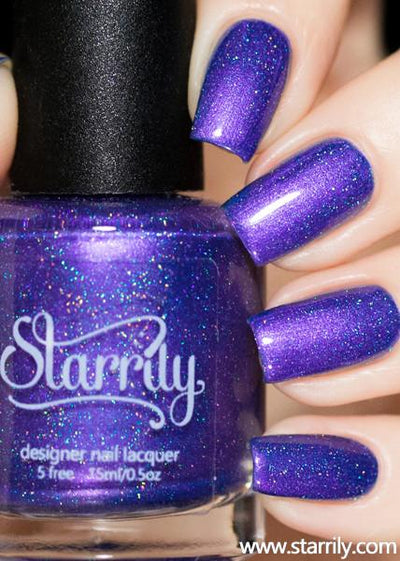 Violet Twilight by Starrily, blue-violet holographic shimmer with scattered blue-teal holo particle scatter under studio lighting, bottle held in a light hand