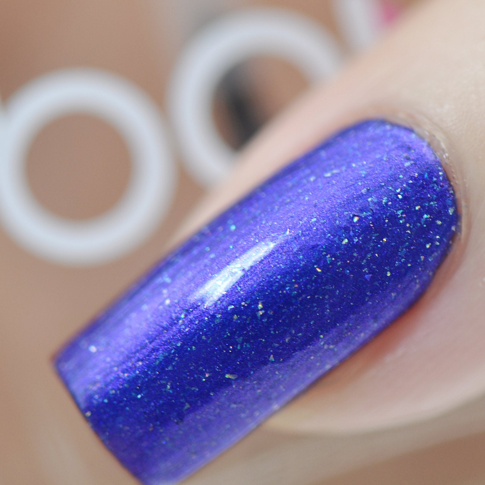 Violet Twilight by Starrily, blue-violet holographic shimmer with iridescent flecks and blue duochrome shift in studio light, on a light skin tone hand
