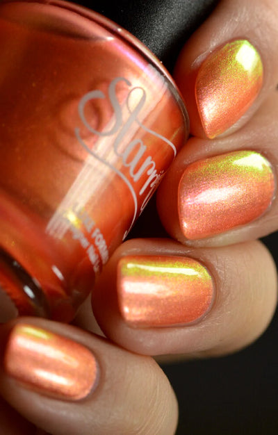 Moon Sugar by Starrily, warm orange shimmer mid-shift from golden peach to electric yellow-green duochrome flash, bottle held in a light-medium hand