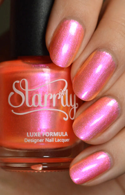 Moon Sugar by Starrily, coral-orange to hot pink multichrome shimmer with warm golden highlights, bottle held in a light-medium hand