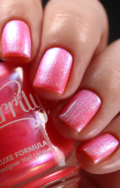 Moon Sugar by Starrily, vivid coral-pink shimmer catching green and gold micro-shimmer particles mid pink-to-orange shift, on a light skin tone hand