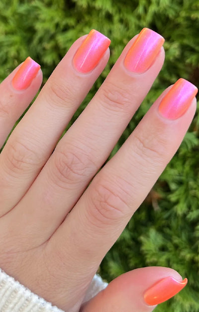 Moon Sugar by Starrily, neon coral-orange and hot pink iridescent multichrome shimmer in bright natural daylight, on a light skin tone hand