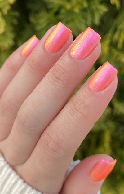 Moon Sugar by Starrily, pink-to-orange color-shifting shimmer with gold and subtle green shimmer highlights in bright outdoor daylight, on a light skin tone hand
