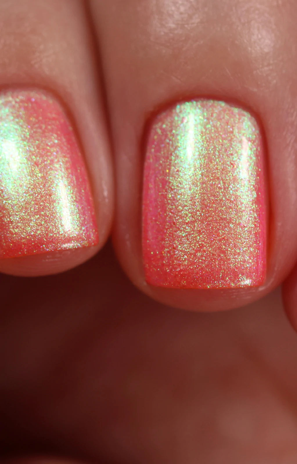 Nectar by Starrily, coral-pink multichrome shimmer blazing chartreuse at highlight zones with gold-to-green shift, on a light skin tone hand