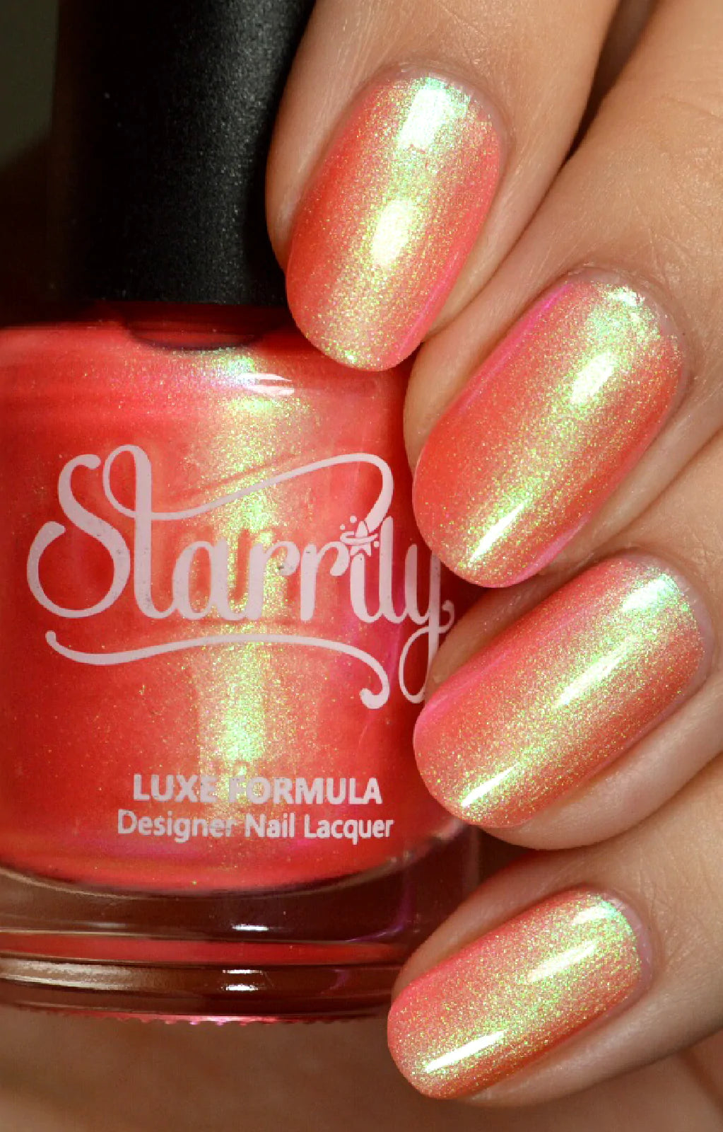 Nectar by Starrily, coral-pink duochrome shimmer with strong yellow-green color shift, bottle held in a light hand