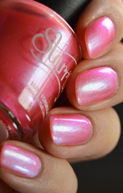 Nectar by Starrily, vivid pink multichrome shimmer shifting to soft green-blue with dense iridescent pearl shimmer, bottle held in a light-medium hand