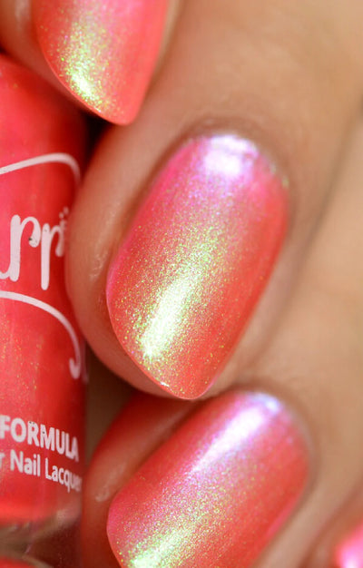 Nectar by Starrily, coral-pink multichrome shimmer with yellow-green and hot pink duochrome shift under studio lighting, on a light-medium skin tone hand