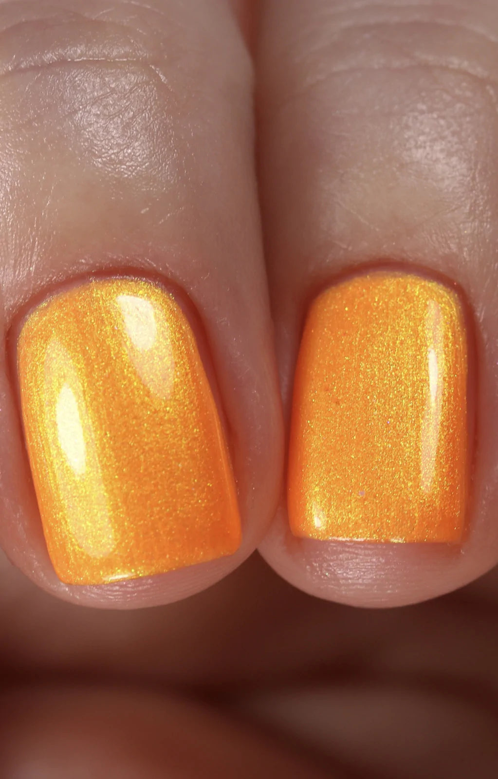 Peach Glow by Starrily, vivid orange base with multidimensional gold-to-green duochrome shimmer particles, on a light skin tone hand