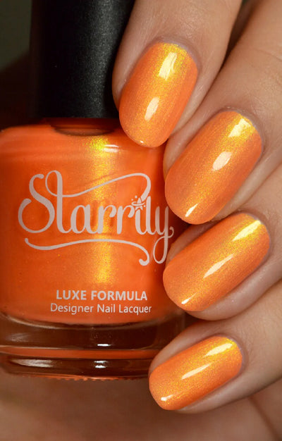 Peach Glow by Starrily, vivid orange shimmer with strong yellow-gold flash in studio light, bottle held in a light hand