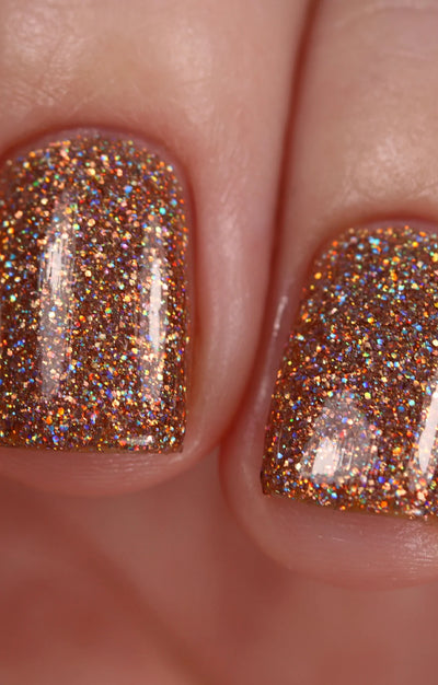 Penny by Starrily, copper and orange-gold micro holographic glitter showing fiery spectral flashes in bright daylight, on a light skin tone hand