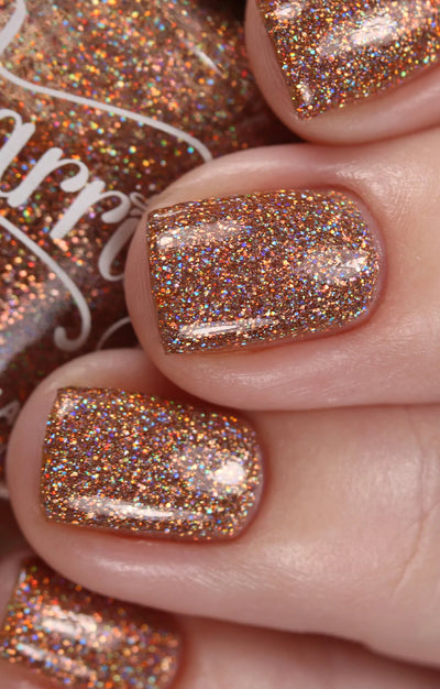 Penny by Starrily, warm copper holographic glitter with gold rainbow scatter in bright daylight, on a light skin tone hand