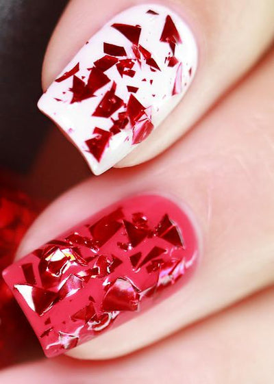 Rose Petals by Starrily, ruby red irregular metallic shard topper shown over sheer white-pink and hot pink creme bases, on a light skin tone hand