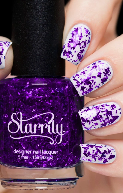 Amethyst by Starrily, purple glitter topper with large irregular violet metallic flakes in a clear base, bottle held in a light skin tone hand