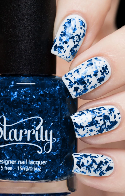 Lapis Lazuli by Starrily, deep royal blue foil flake glitter topper over white creme, layering demo on a light skin tone hand
