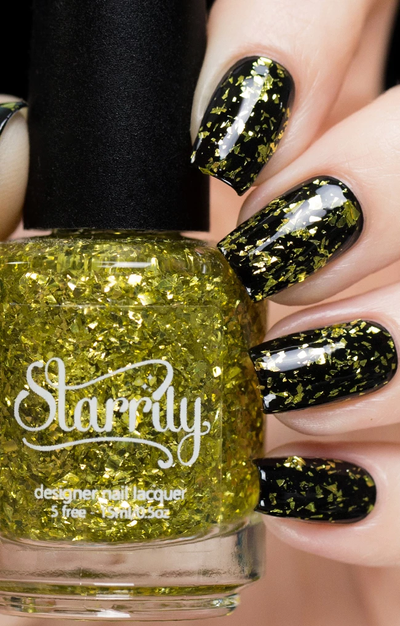 Sphene by Starrily, clear-base glitter topper with large irregular yellow-gold foil flakes, bottle held in a light skin tone hand