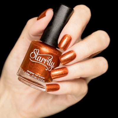 Sunlight (Orange Foil) by Starrily, brilliant copper-orange metallic foil with intense reflective micro-flakie finish, bottle held in a light hand