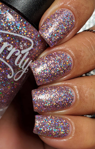 Dollhouse by Starrily, light pink holographic micro-glitter in clear base with full rainbow spectral scatter, on a medium-deep skin tone hand