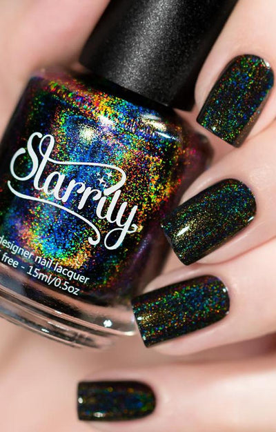 Black Magic by Starrily, jet black holographic glitter with rainbow spectral dispersion showing gold and green sparks, bottle held in a light hand