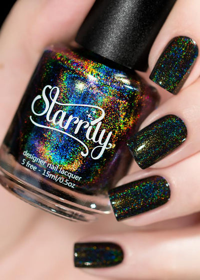 Black Magic by Starrily, jet black holographic glitter with full-spectrum scatter from gold to blue, bottle held in a light hand