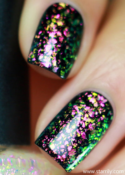 Enchanted by Starrily, iridescent flakie topper with large magenta-pink to electric yellow-green ultrachrome shards over dark base, on a light skin tone hand