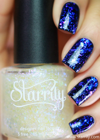 Patronus by Starrily, blue-violet multichrome flakie topper with sheer base, showing electric-to-deep-violet shift over black, bottle held in a light hand