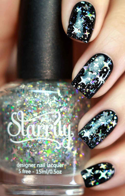 Starry Night by Starrily, holographic glitter topper with star-shaped holo glitters and rainbow spectral flash over black base, bottle held in a light skin tone hand