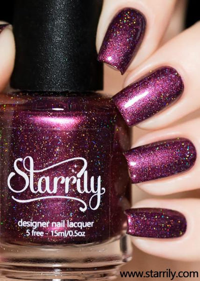 True Blood by Starrily, deep magenta-plum holographic with scattered rainbow sparkle and pink holographic highlight shift, bottle held in a light hand