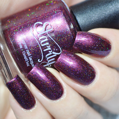 True Blood by Starrily, deep maroon-burgundy holographic with linear holo scatter and pink-to-purple shimmer shift, on a light skin tone hand