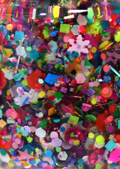 Toy Story by Starrily, multicolor glitter topper, macro close-up of bottle interior showing mixed-shape glitters including snowflakes, hexagons, circles, and bars in red, teal, hot pink, and neon yellow