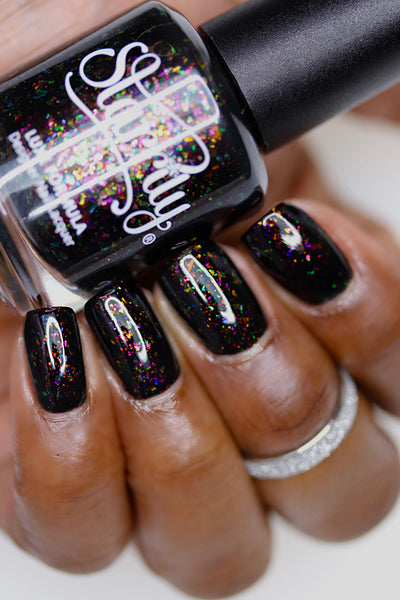 Planet X by Starrily, black flakie jelly showing dense magenta and gold iridescent flake flash, bottle held in a deep hand