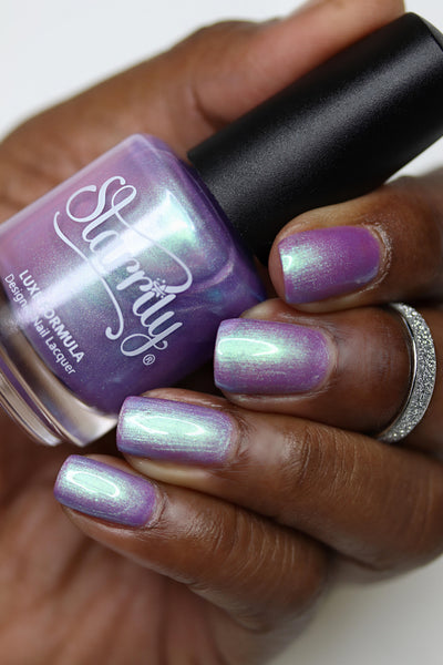 Fairy Fountain by Starrily, light purple shimmer with strong green-to-purple color-shifting shift, bottle held in a rich hand
