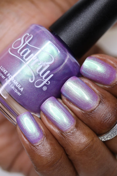 Fairy Fountain by Starrily, light purple base with vivid green-mint iridescent duochrome shimmer, bottle held in a rich hand